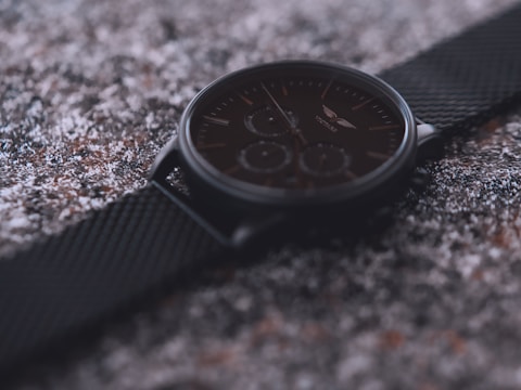 Dynamic shot of a sport watch with a rubber strap and chronograph features against a textured black surface.