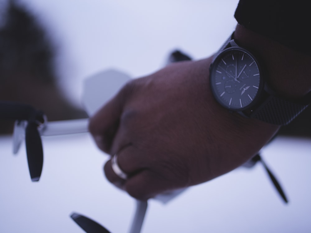 shallow focus photo of person wearing round black chronograph watch