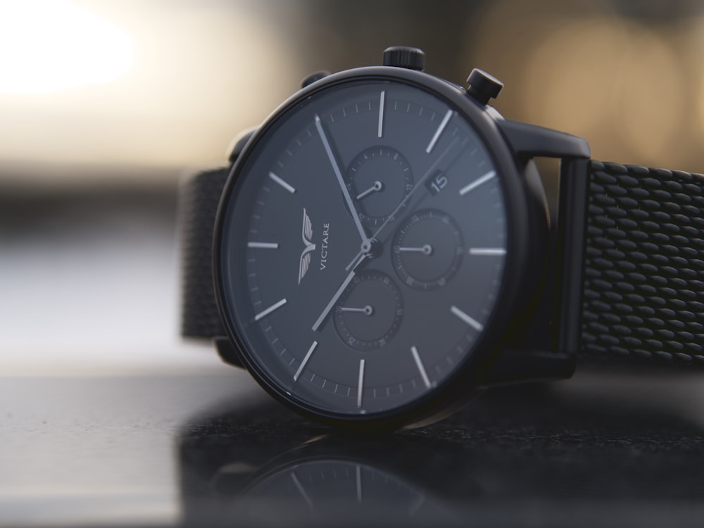 shallow focus photo of round black chronograph watch