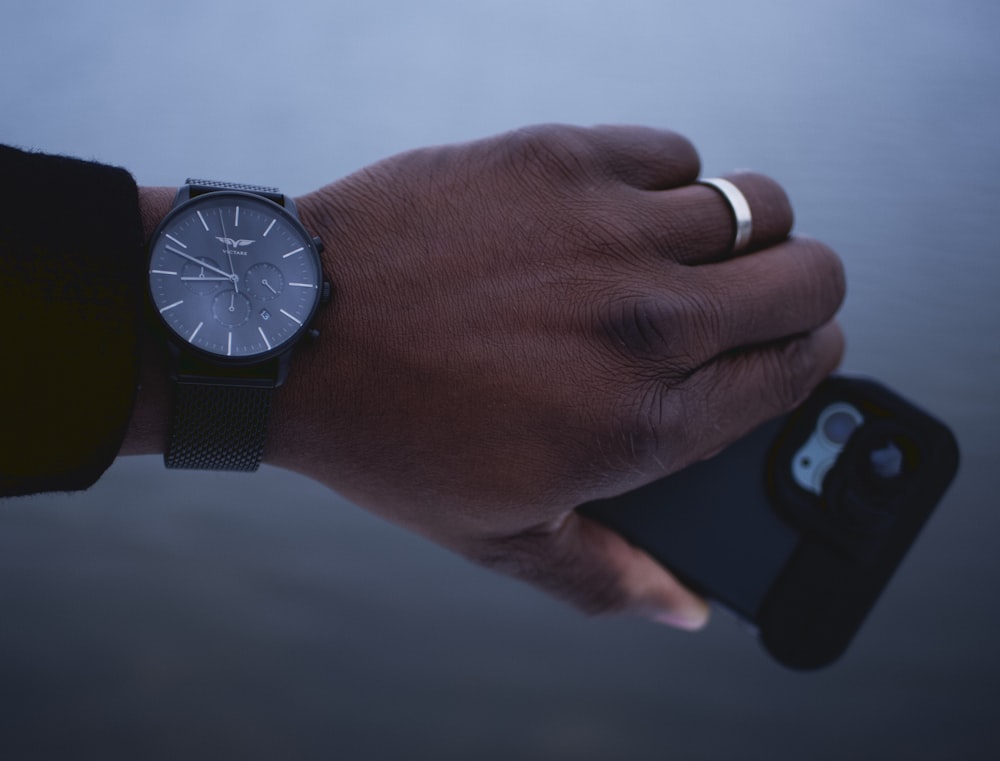 shallow focus photo of person wearing round black chronograph watch