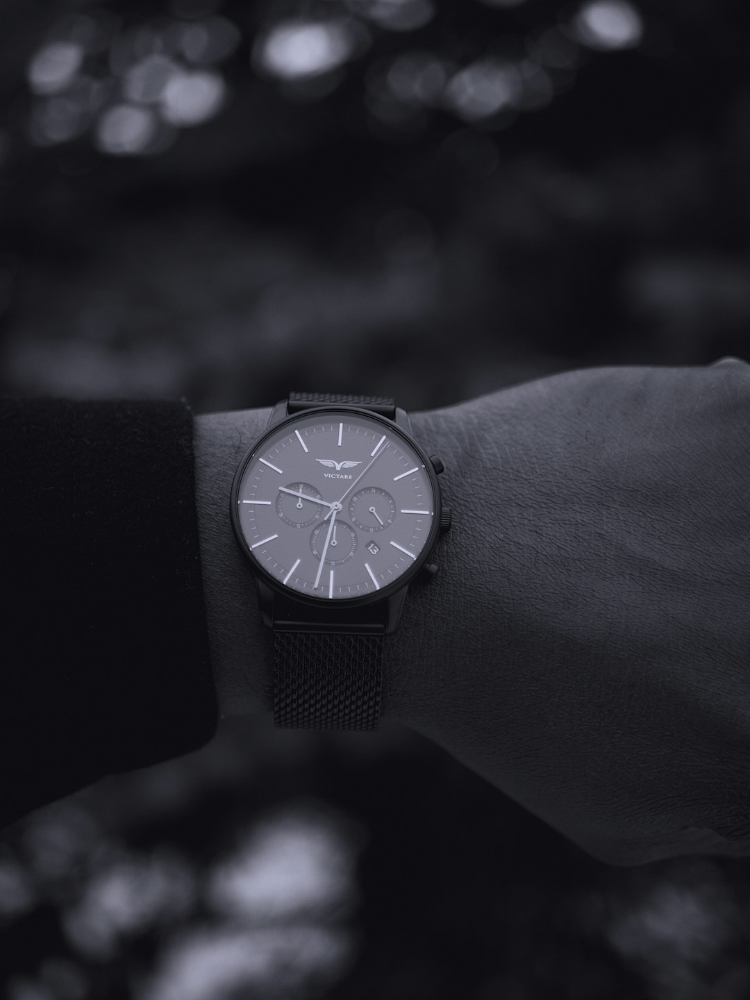 grayscale photo of person wearing round black chronograph watch