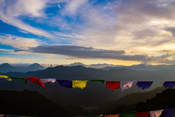 A serene sunset over the rugged mountains of Leh Ladakh, with prayer flags fluttering gently in the breeze.