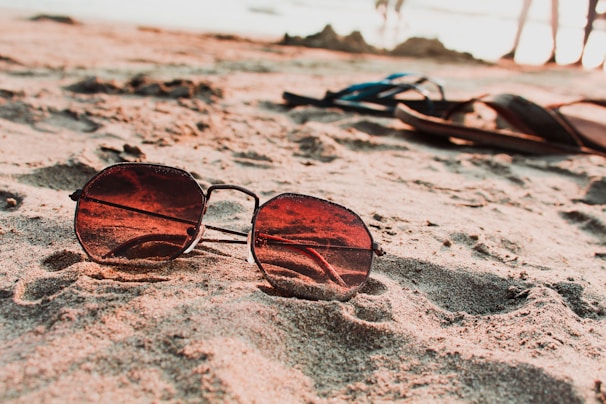 Bright sunlight reflecting off sleek black sunglasses on a summer beach towel