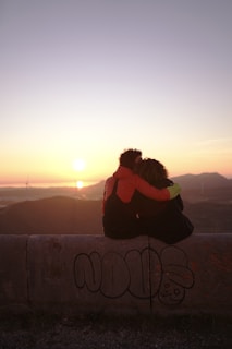 person hugging person while sitting during golden hour