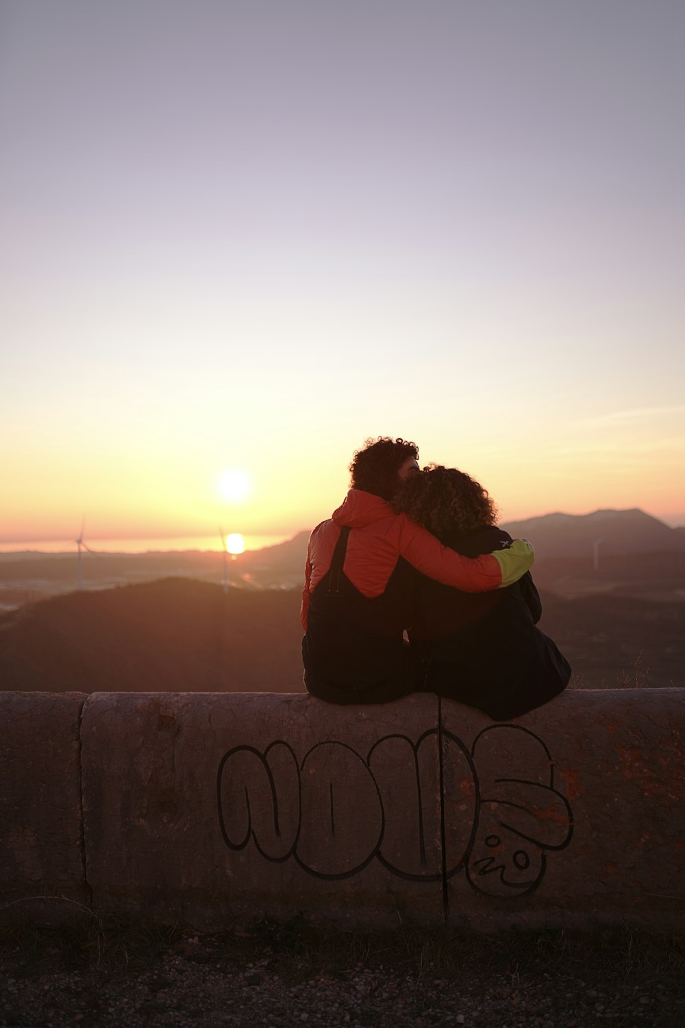 person hugging person while sitting during golden hour