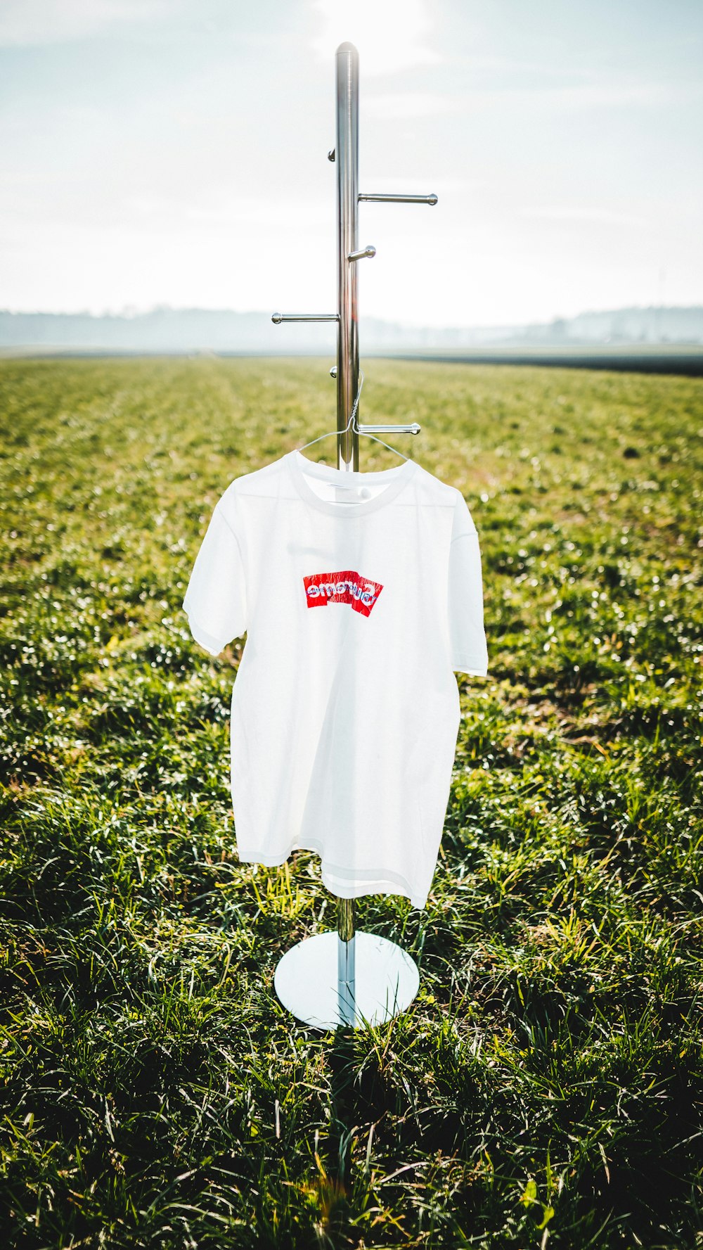hanged white and red crew-neck shirt on display rack on green grass