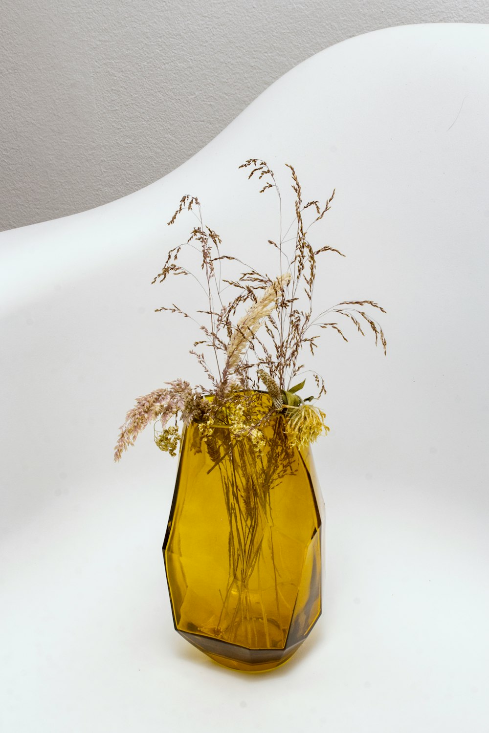 grasses in yellow translucent glass vase