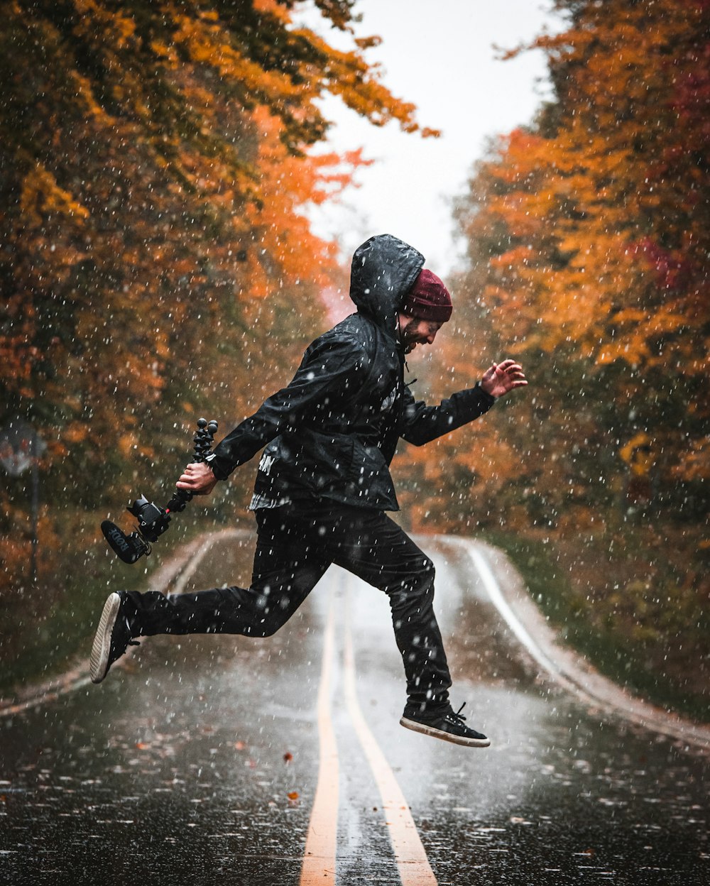 Fotografía de lapso de tiempo de un hombre saltando en una carretera mientras llueve