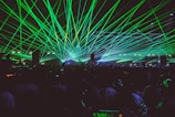 A nighttime event scene with colorful laser lights cutting through the crowd’s excitement.