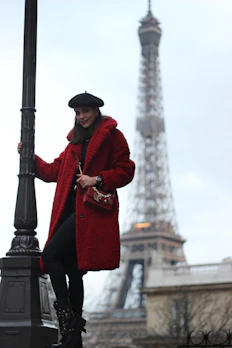A stylish model wearing a vibrant red beret in a sunlit Parisian street.