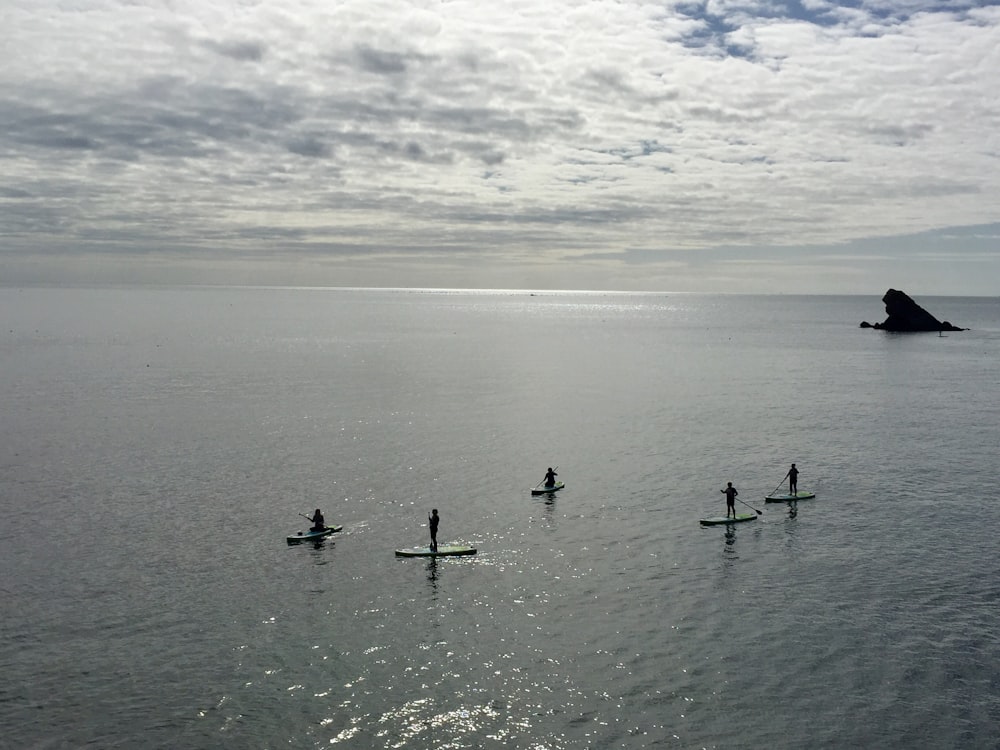 five people paddle boarding on sea