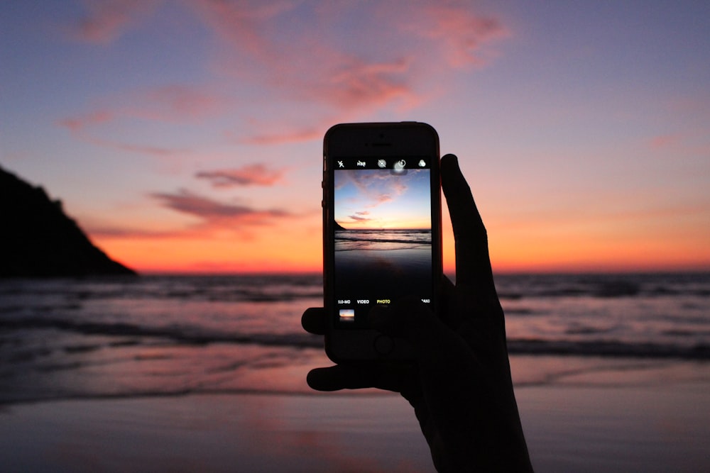 personne prenant une photo de la mer à l’aide d’un smartphone