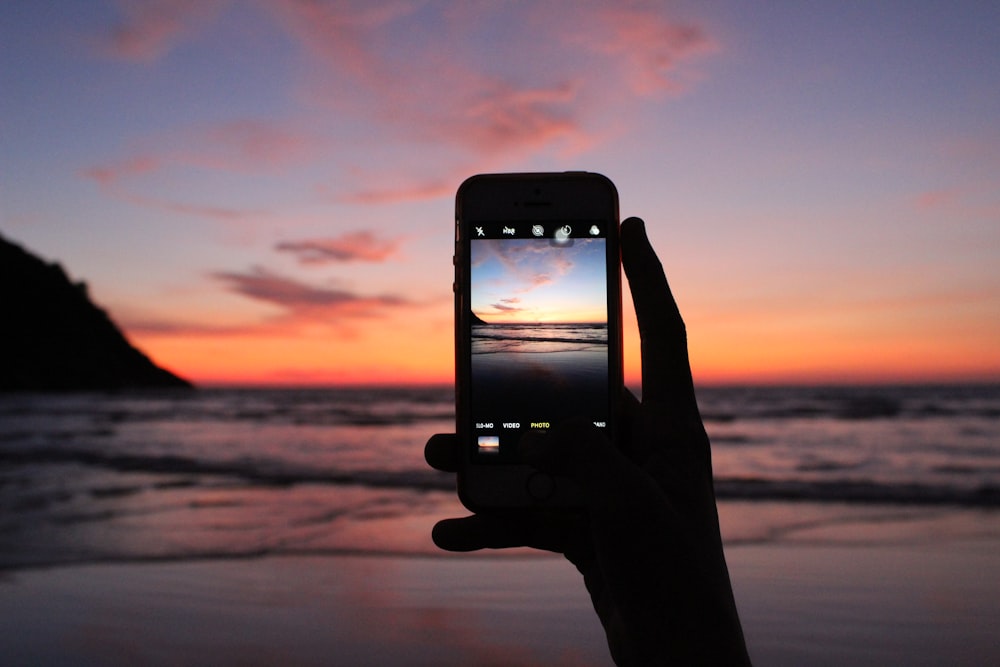 Person, die mit dem Smartphone ein Foto vom Meer macht