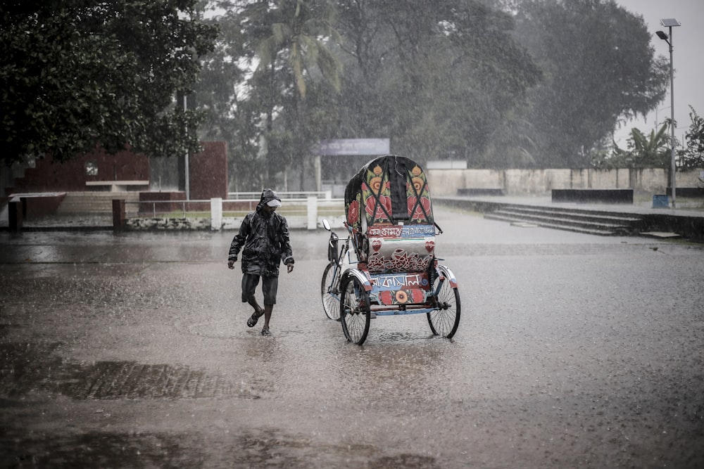 man walking beside trike during rain