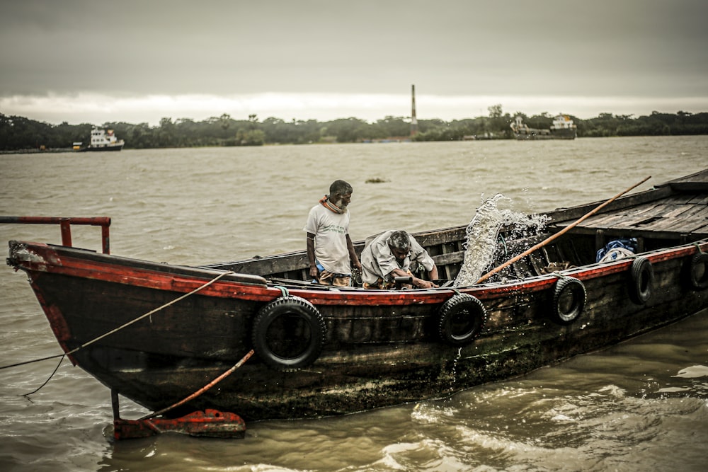 selective focus photography of two men on black fishing boat