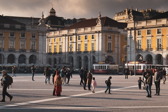 people walking on paved road in Praça do Comércio Portugal