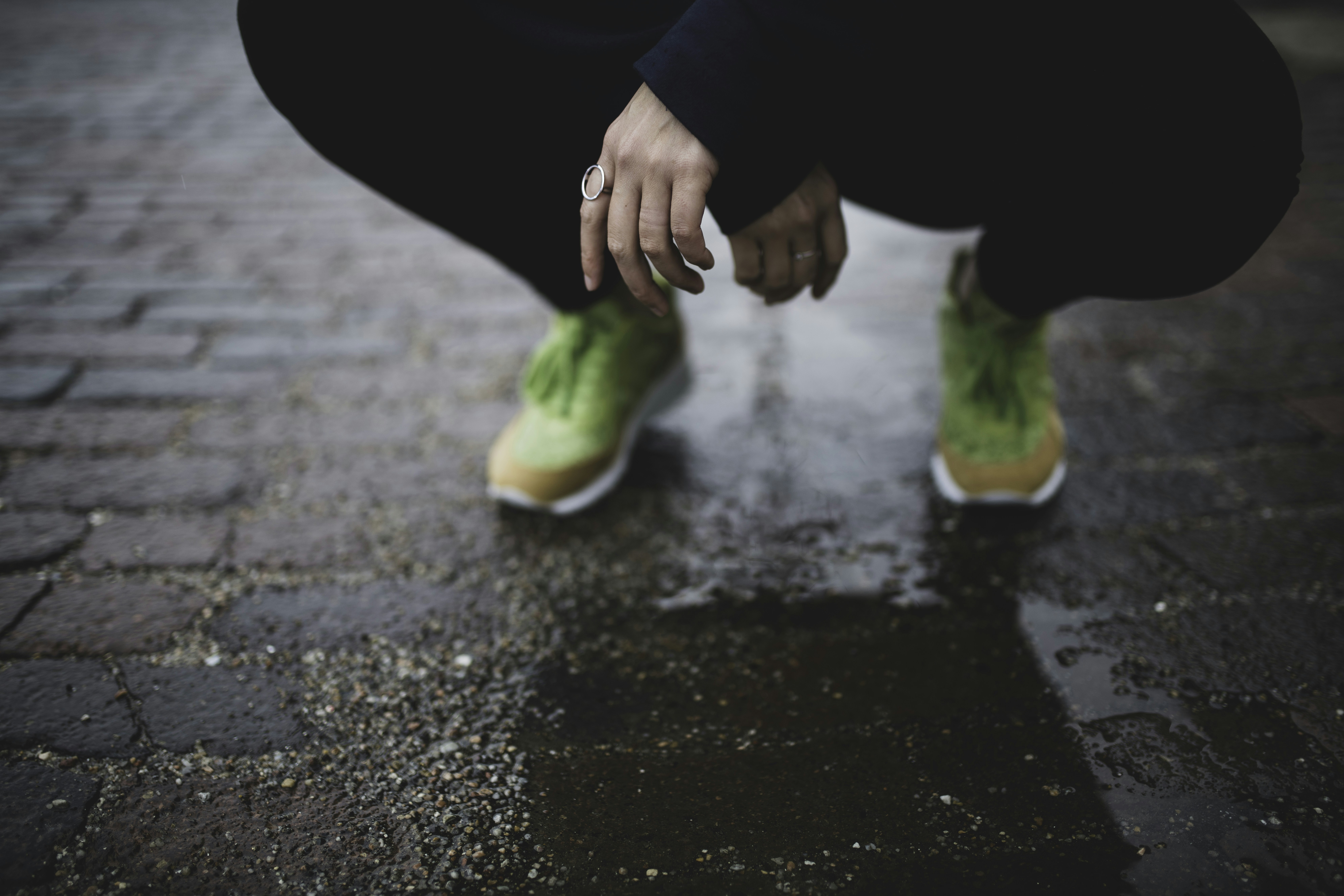 person squatting on brick road during day kansas teams background