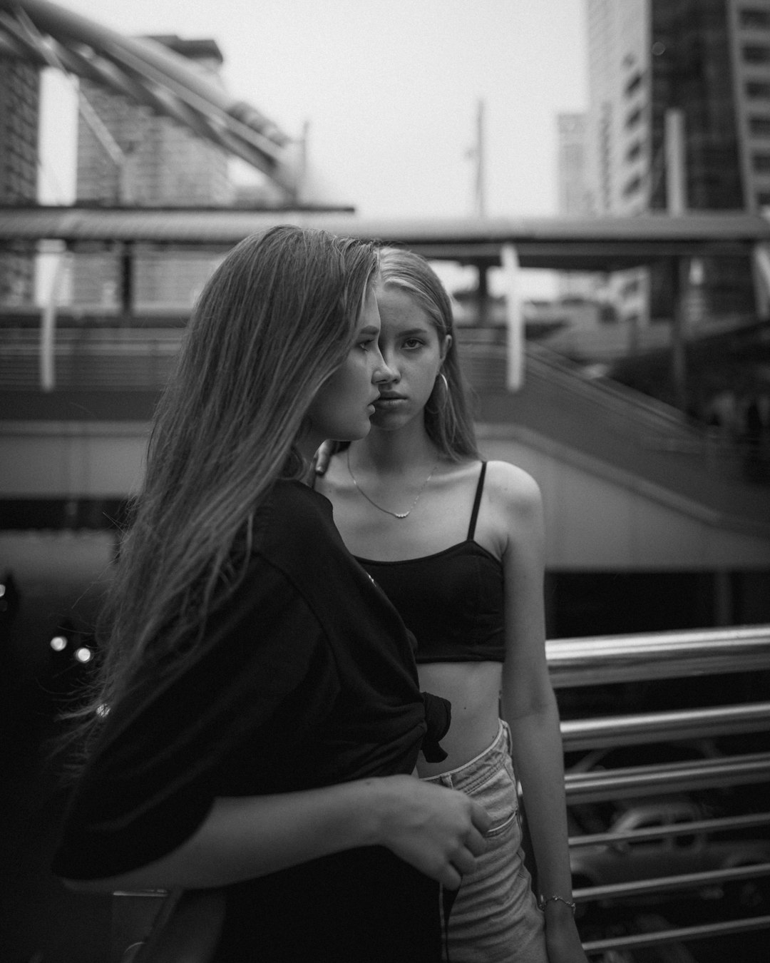 grayscale photo of two women leaning on metal balustrade