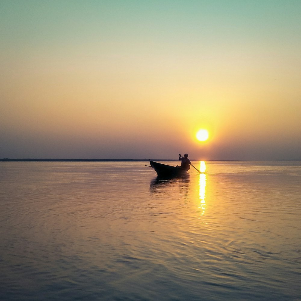 Silhouette eines Mannes auf einem Boot während der goldenen Stunde
