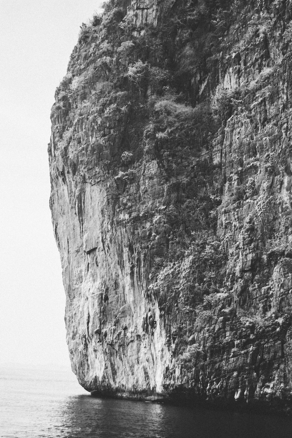 uma foto em preto e branco de uma grande rocha no oceano