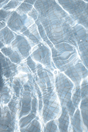 Close-up of shimmering pool water reflecting the villa’s ambient lighting.