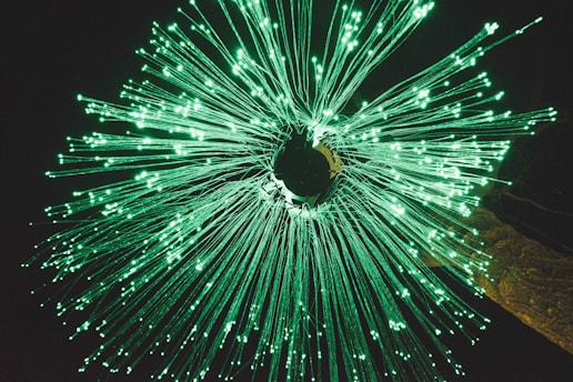 Radiating fibers illuminate in bright green, resembling an explosive burst of light against a dark background.