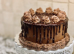 A rich chocolate cake with intricate piping and a glossy ganache finish