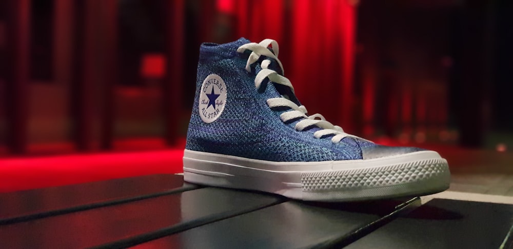 ungepaart blauer Converse Schuh auf schwarzem Untergrund