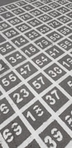 A grid of numbered squares painted on a dark gray asphalt surface. The numbers range from 1 to 9, with some numbers repeated multiple times in a random order. The squares are outlined in white paint.