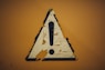 a triangle shaped sign on a yellow wall