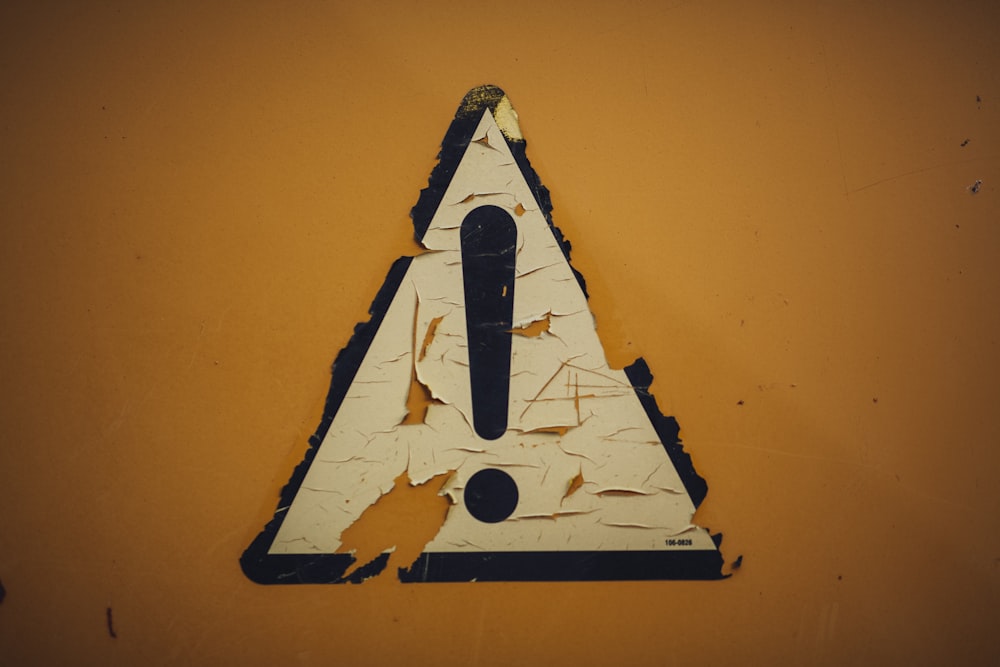 a triangle shaped sign on a yellow wall