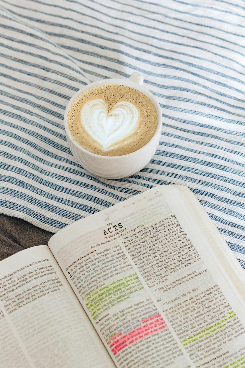 taza de café marrón junto al libro blanco