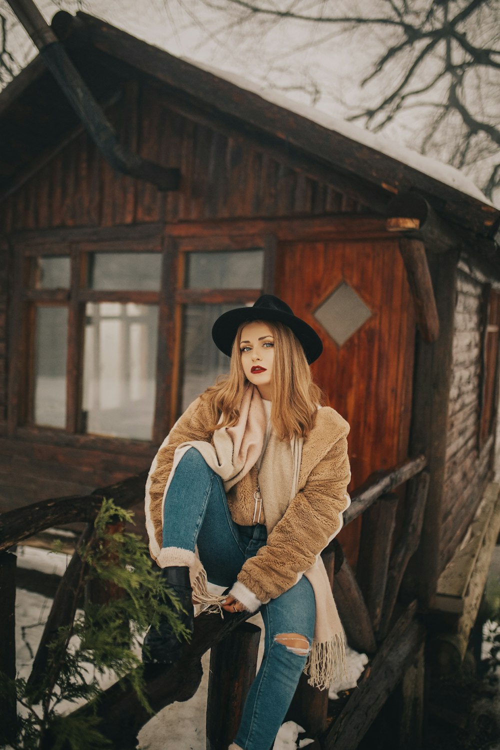 woman sitting on black wooden fence