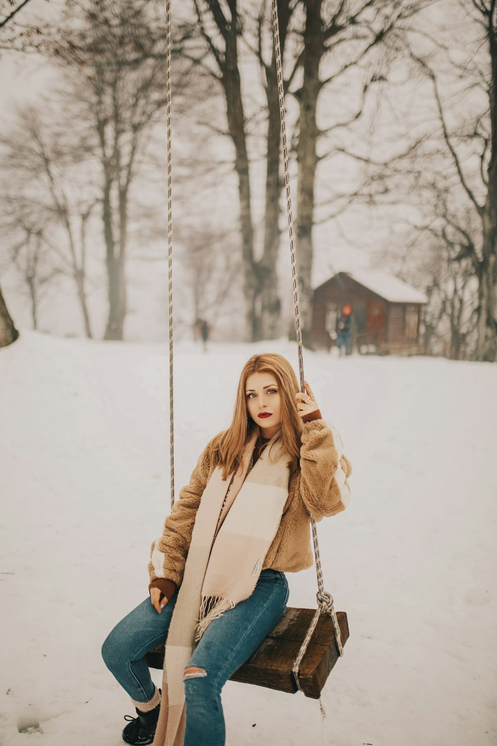 woman sitting on brown and beige swing during snow season