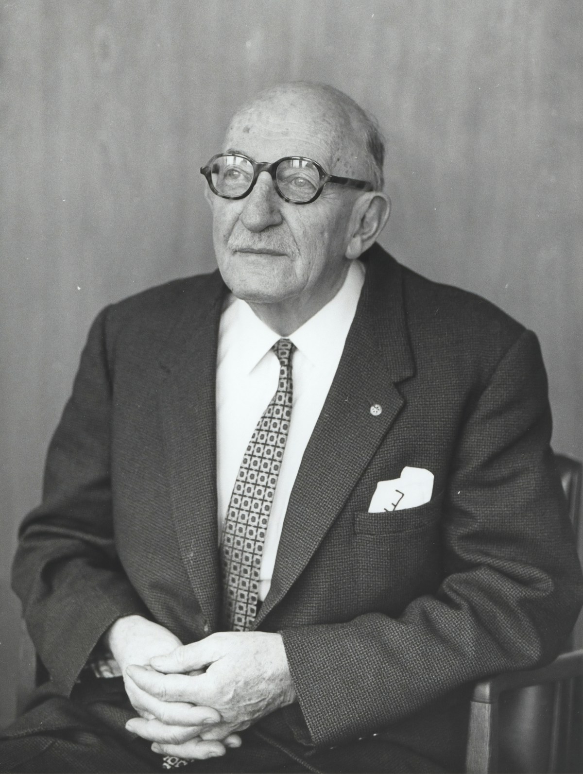 Editorial black and white portrait of a seated man in a suit