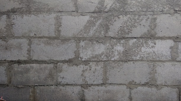 A close-up view of a rough, unfinished brick wall with visible mortar between the bricks.