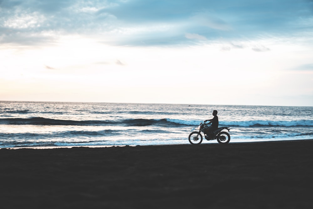 silhouette of man riding motorcycle beside seashore