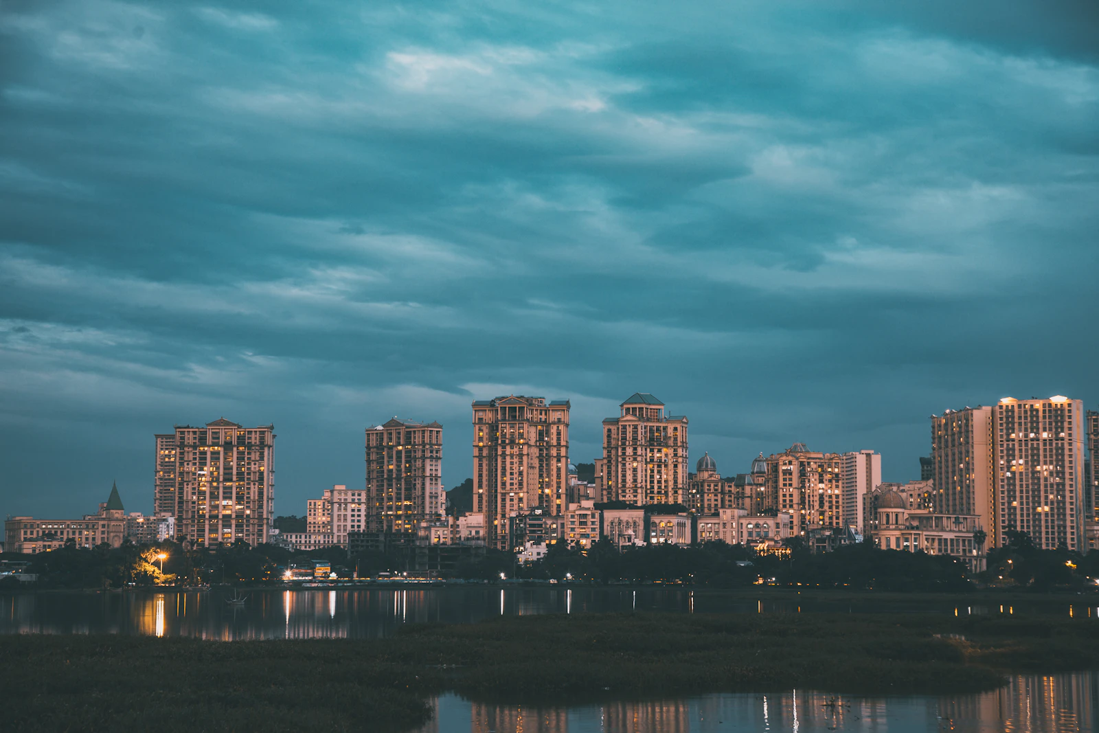 Lit city buildings beside a lake, similar to the Powai skyline
