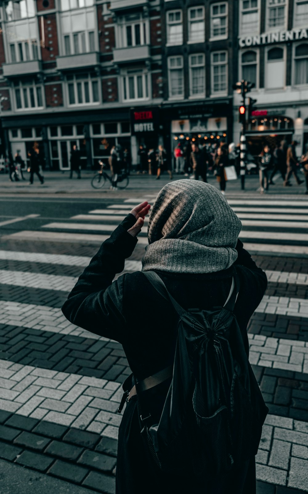 person in black and white hijab standing on sidewalk during daytime