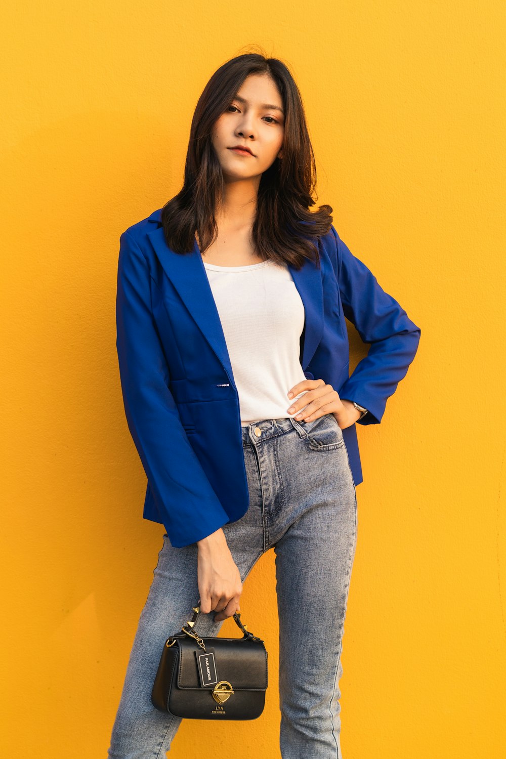 Mujer en chaqueta de traje azul de pie junto a la pared