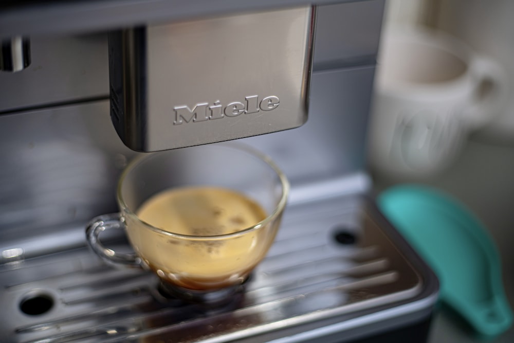 clear glass mug on gray espresso machine