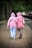 A happy woman in a pastel pink hoodie holding a matching hoodie with her partner.