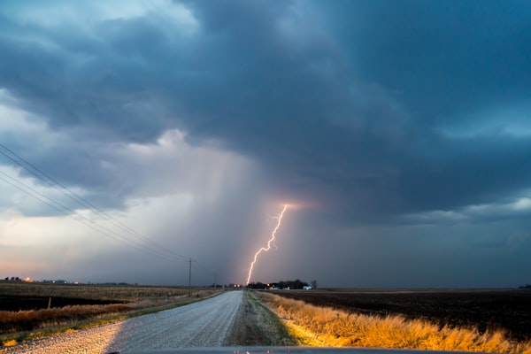 a bolt of lightning from a dark purple sky on a road up ahead