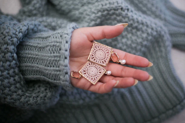 un par de aretes de macrame sobre una mano.