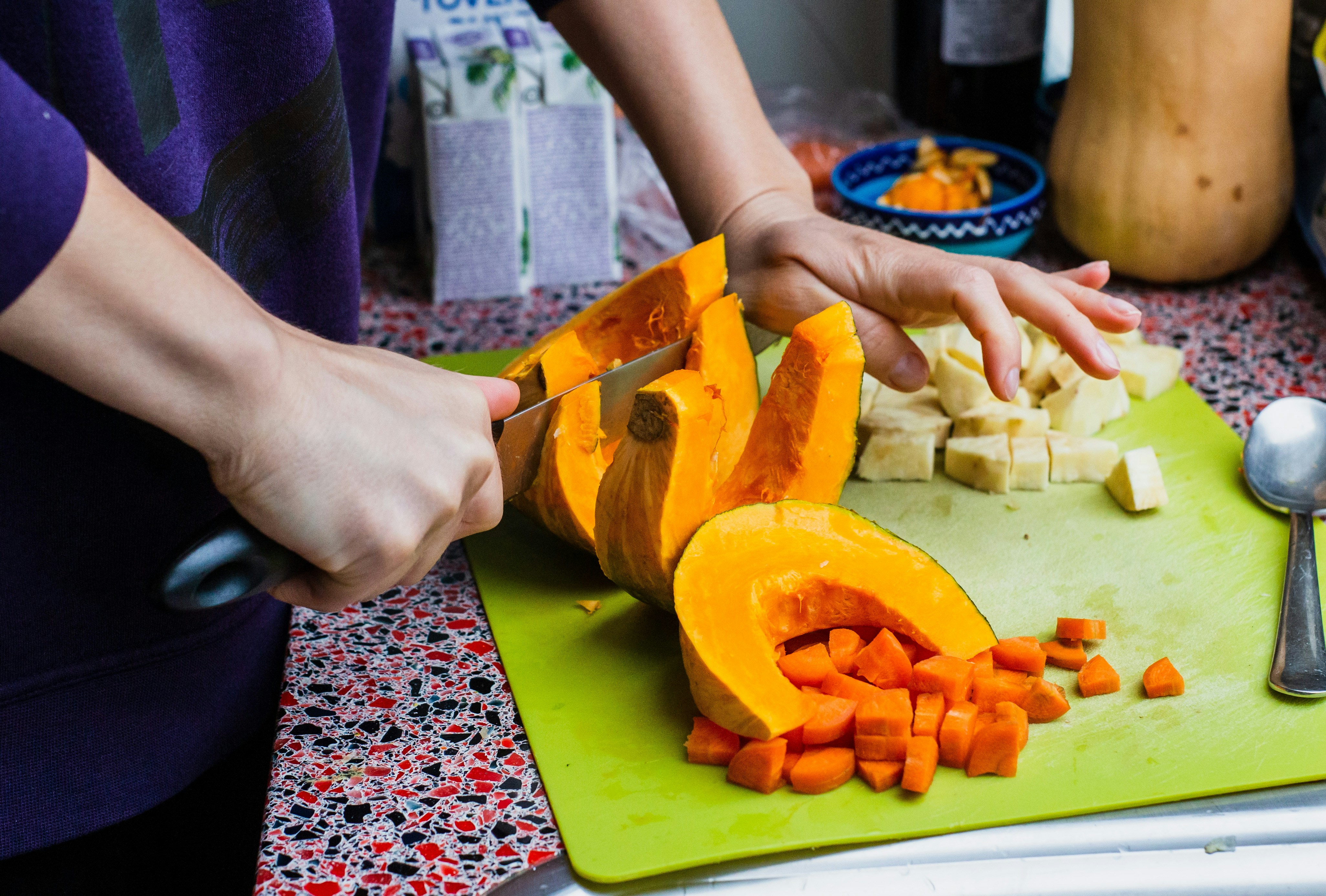 chef safely dicing a butternut squash on a stable cutting board - curried butternut squash soup vegan