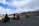 A group of motorcyclists pausing on a scenic overlook with mountains stretching into the distance under a clear blue sky.