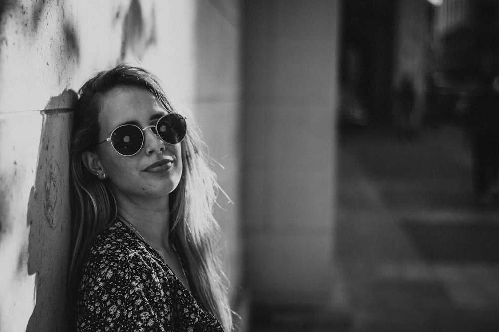 grayscale photography of woman leaning on wall