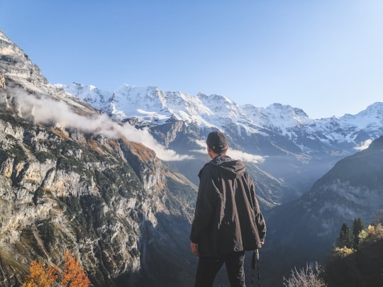 man standing in front of black ad white mountain ranges in Lauterbrunnen Switzerland