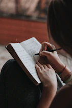woman writing in notebook with pen