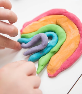 Child's hands building a rainbow out of Playdoh